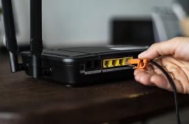 Man plugging in an ethernet cable to a wireless router